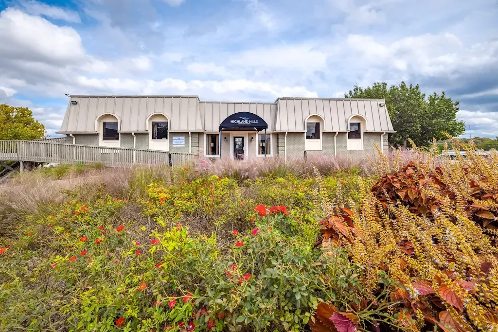 A large white house is surrounded by a field of flowers.