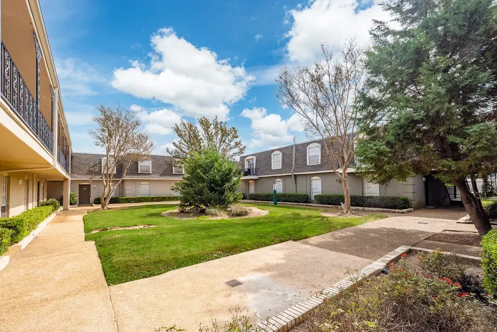 A large lawn in front of a building with a walkway leading to it.
