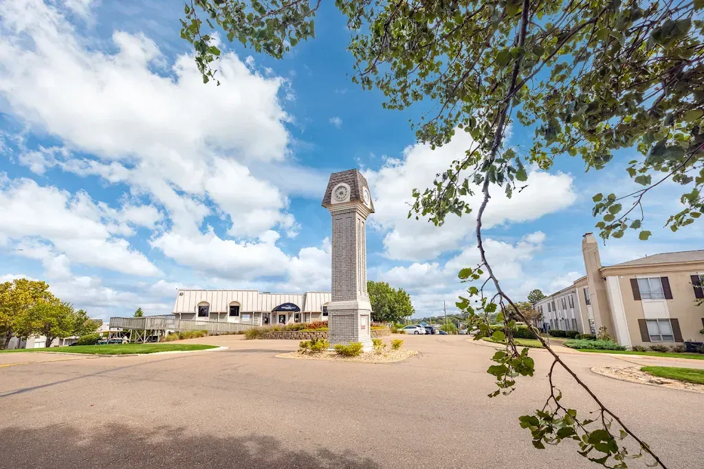 There is a clock tower in the middle of a parking lot.