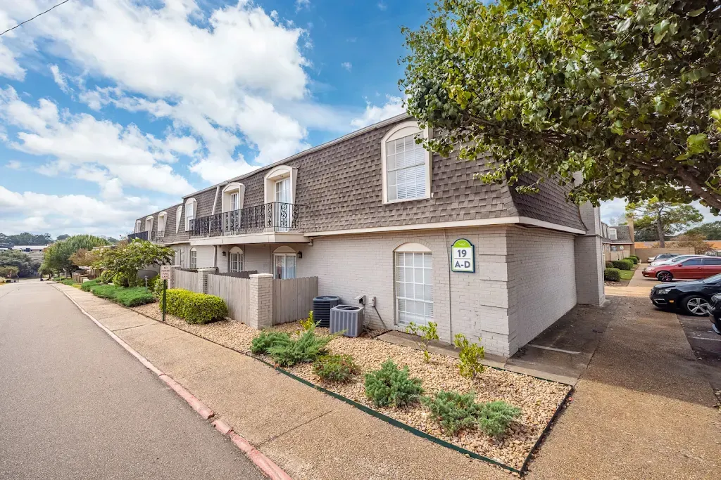 A white apartment building with a parking lot in front of it.