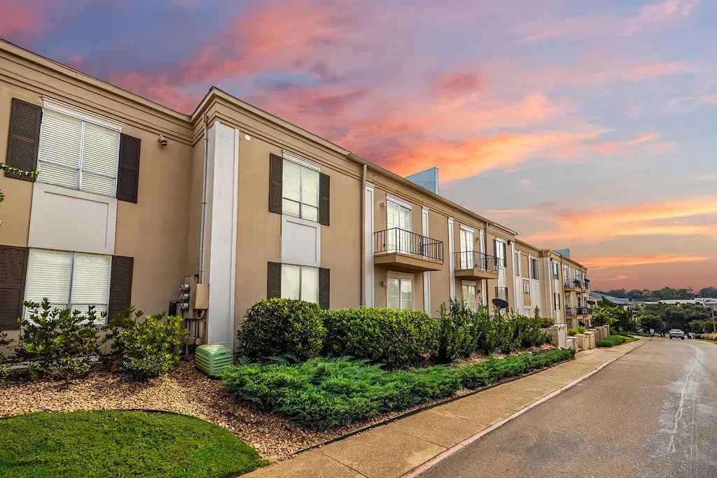 A large apartment building with a lot of windows and a sunset in the background.