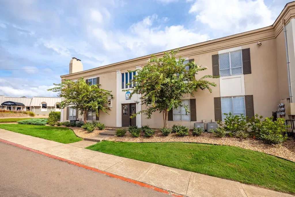 A large apartment building with a lush green lawn in front of it.