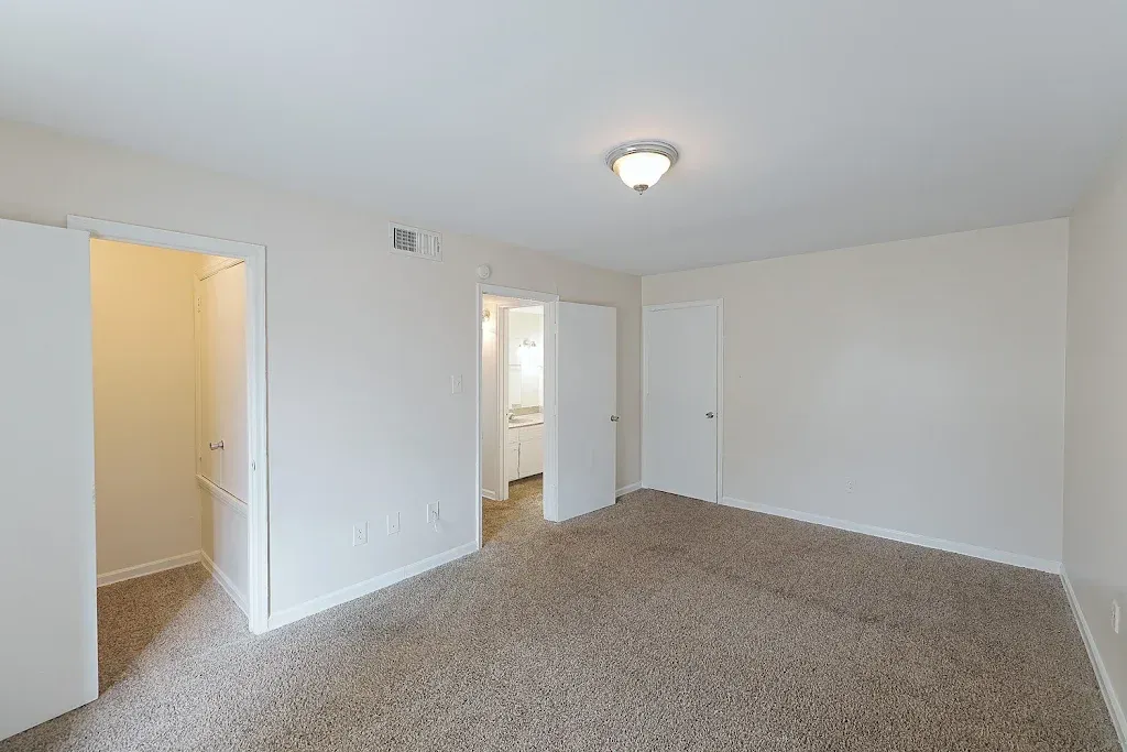 An empty bedroom with a carpeted floor and white walls.