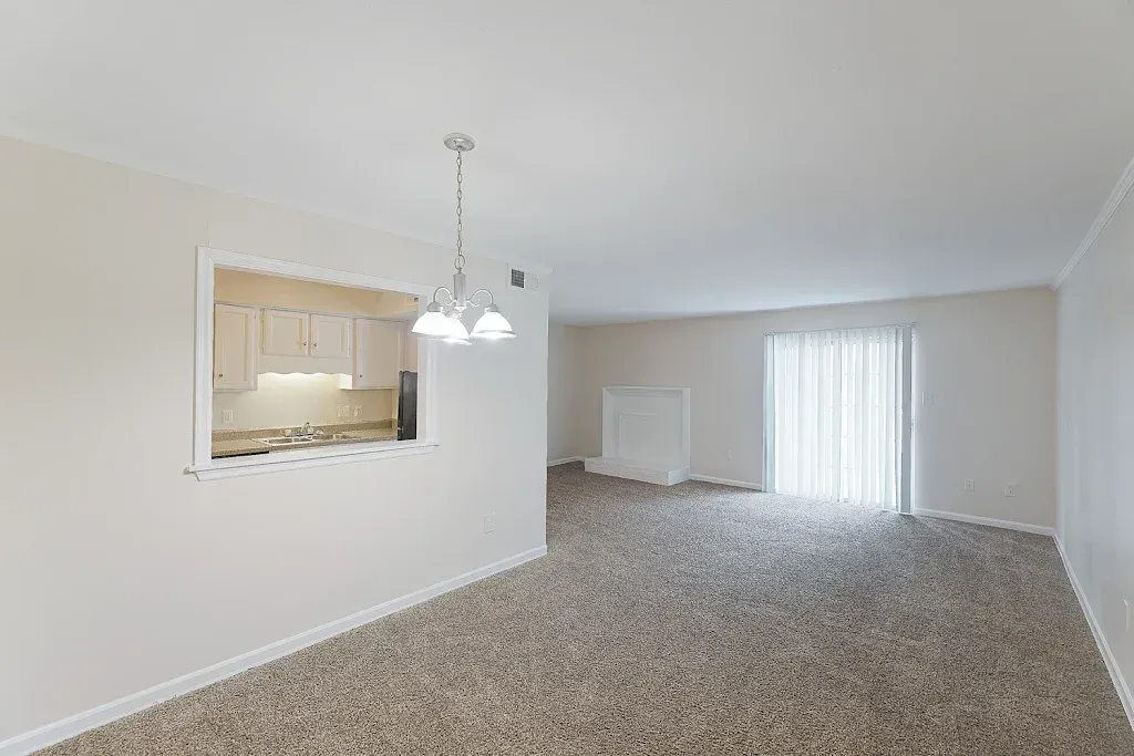 An empty living room with a sliding glass door and a chandelier.