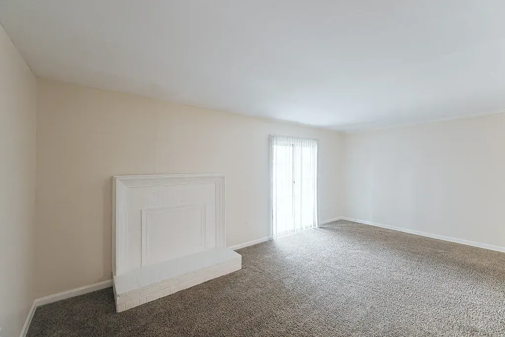 An empty living room with a fireplace and sliding glass doors.