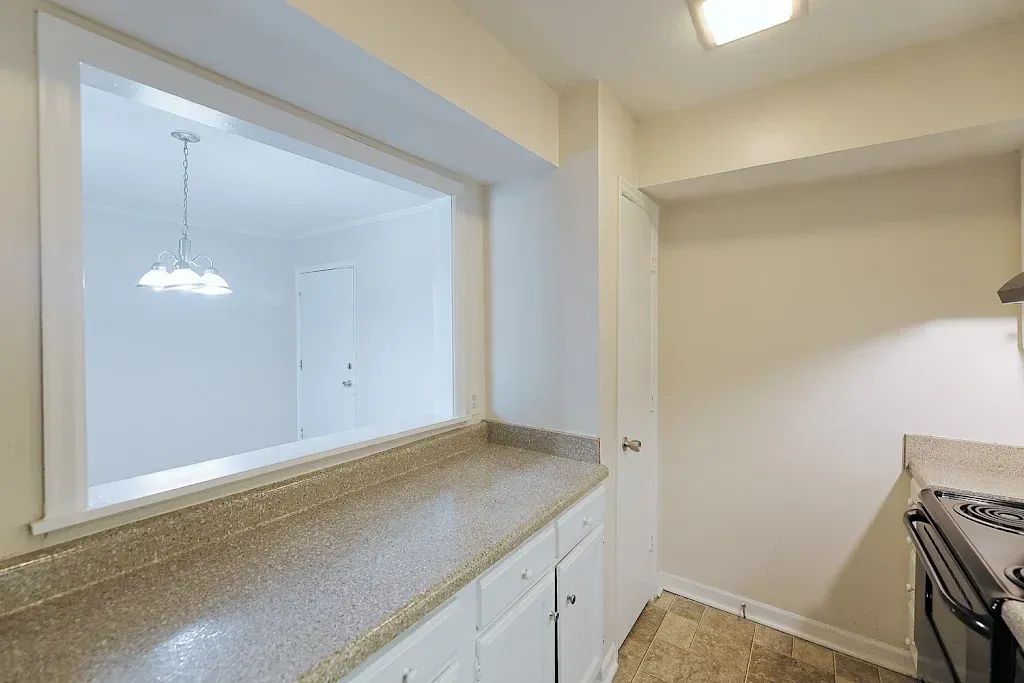 A kitchen with granite counter tops , a stove , and a window.