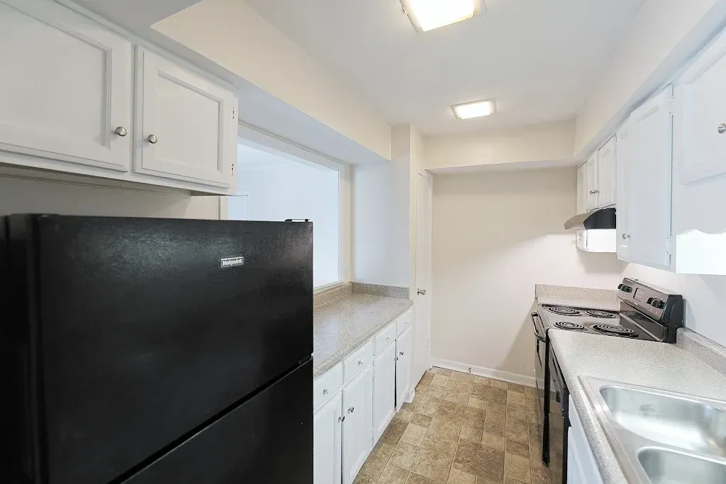 A kitchen with white cabinets and a black refrigerator