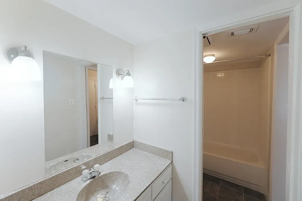 A bathroom with a sink , mirror and tub.