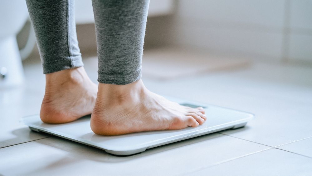 Woman in white underwear holding hands over abdomen.