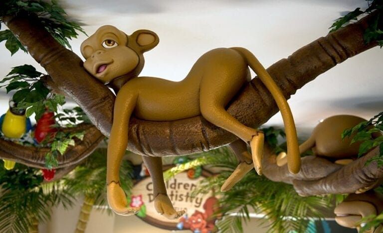 Cartoon monkey resting on a tree branch, part of a children's dentistry office decor.