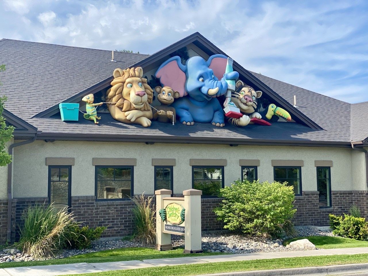 Building with animal sculptures on the roof. Includes a lion, elephant, and other creatures; green sign out front.