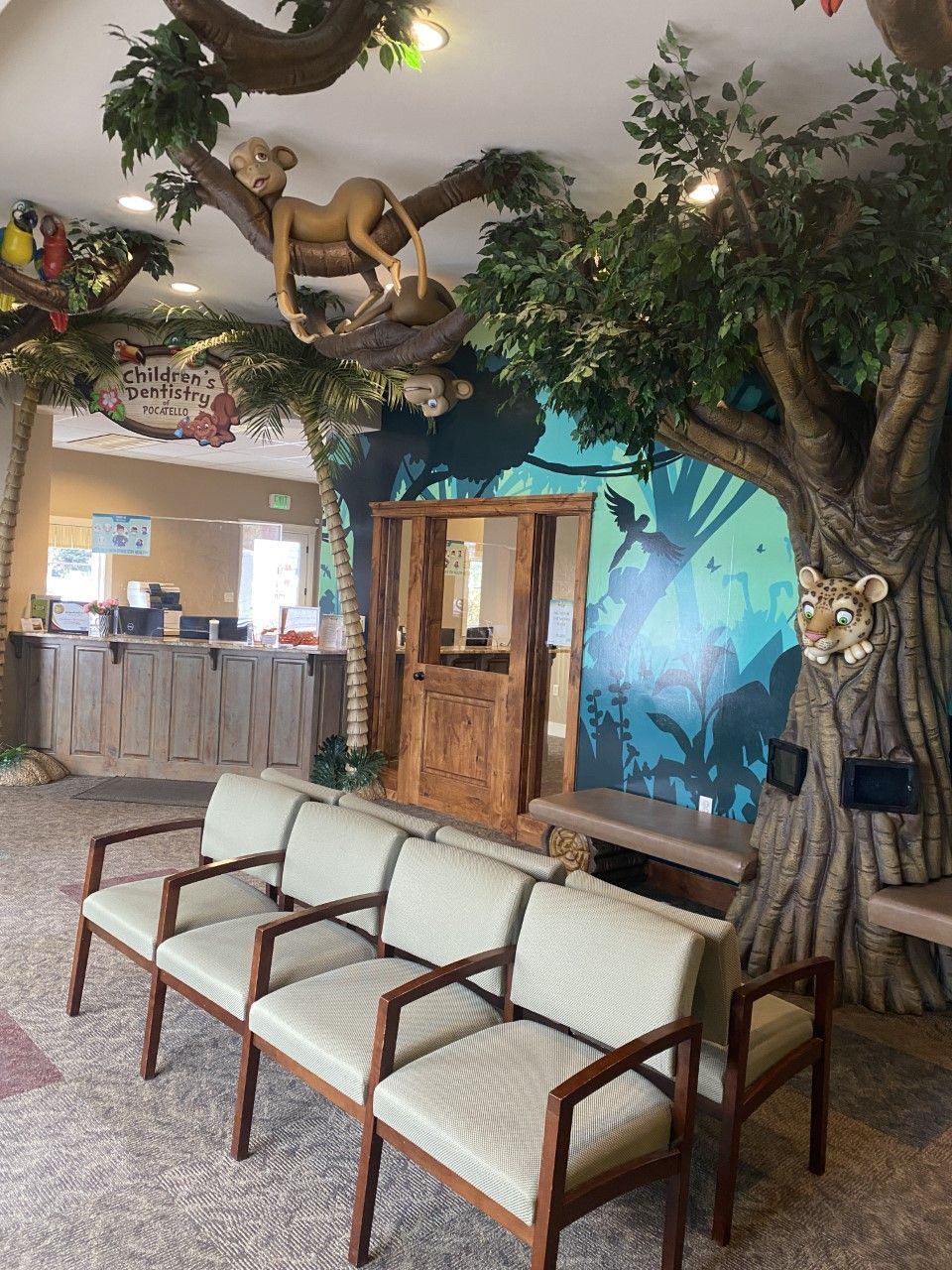 Waiting room decorated as a jungle, with chairs, tree murals, and lion statues.