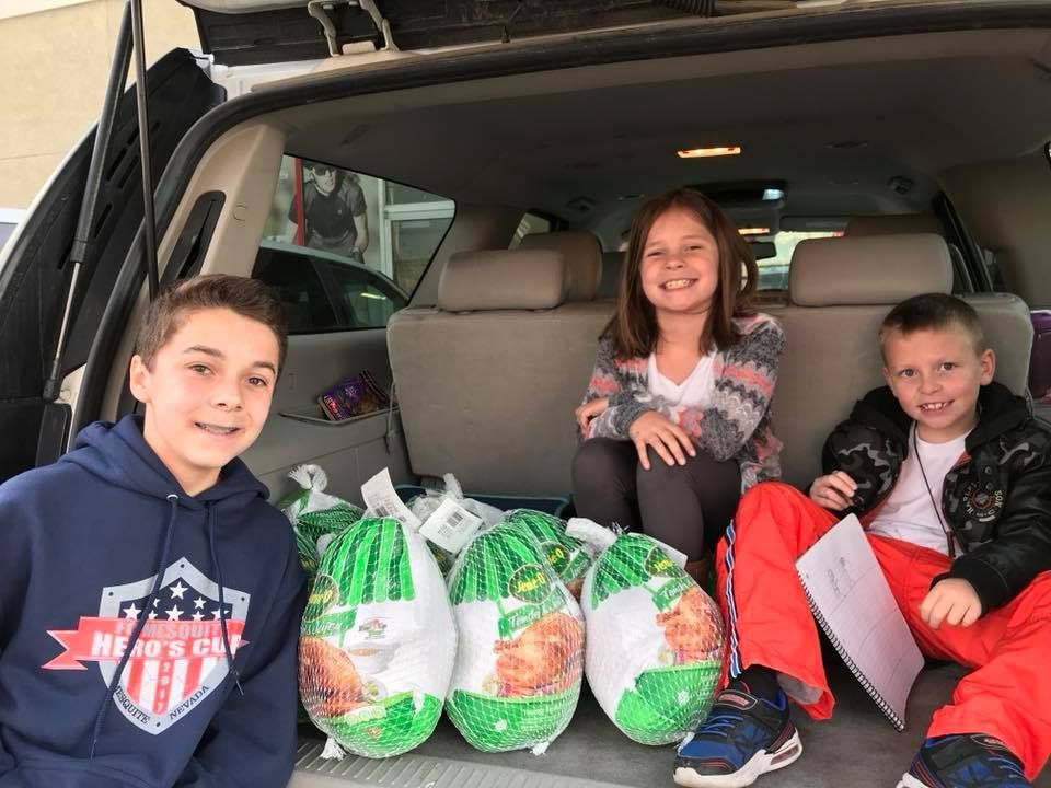 Children seated in an open vehicle trunk, smiling with turkeys.