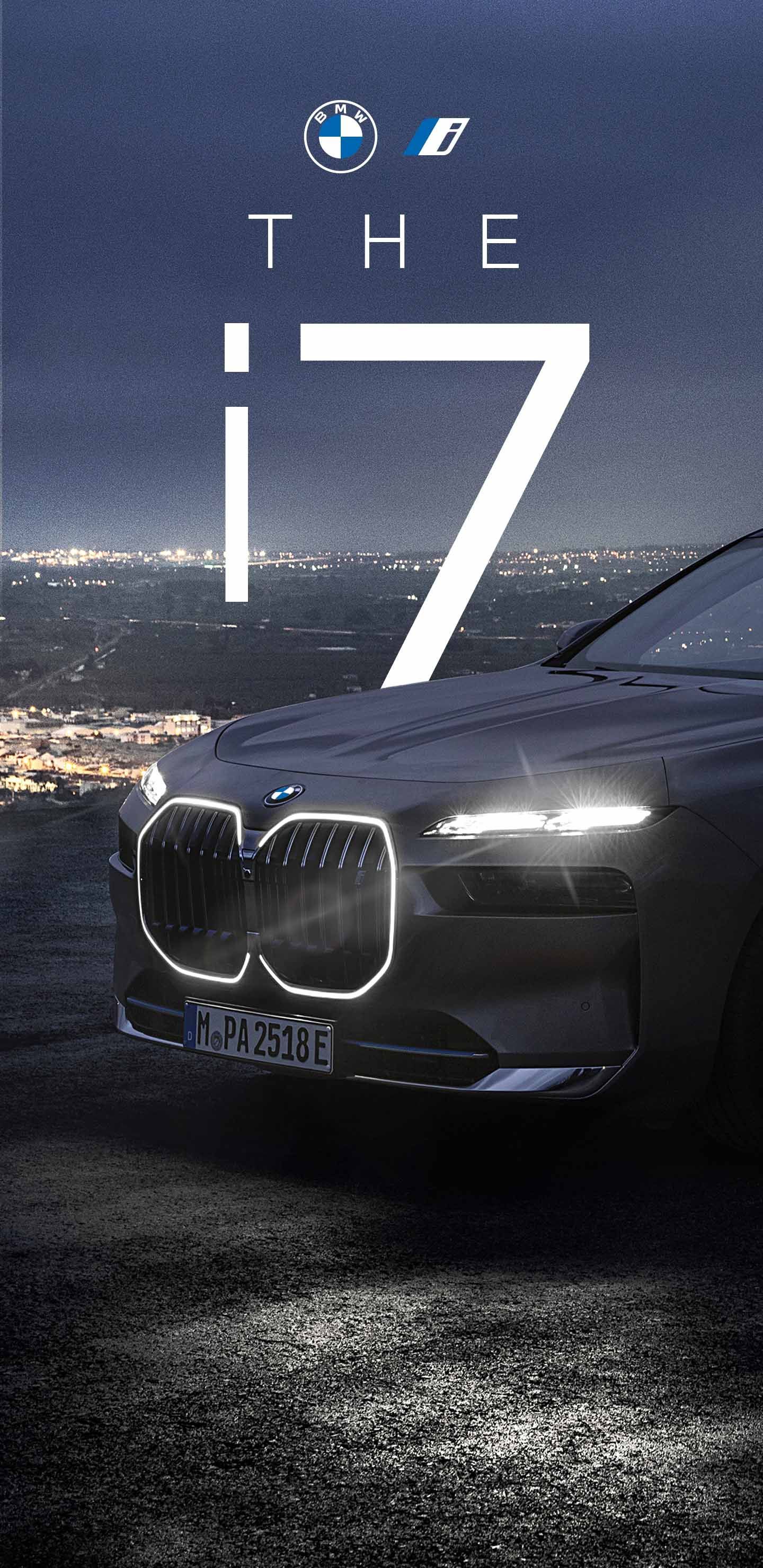 BMW i7 electric car at night, headlights illuminated, cityscape background.