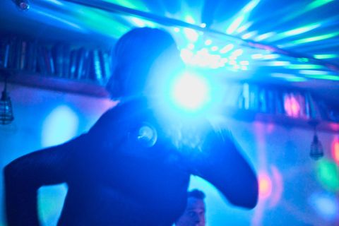 Person dancing in a club with blue and colorful lights.