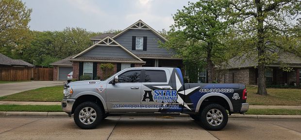 A truck with a trailer attached to it is parked in front of a house.