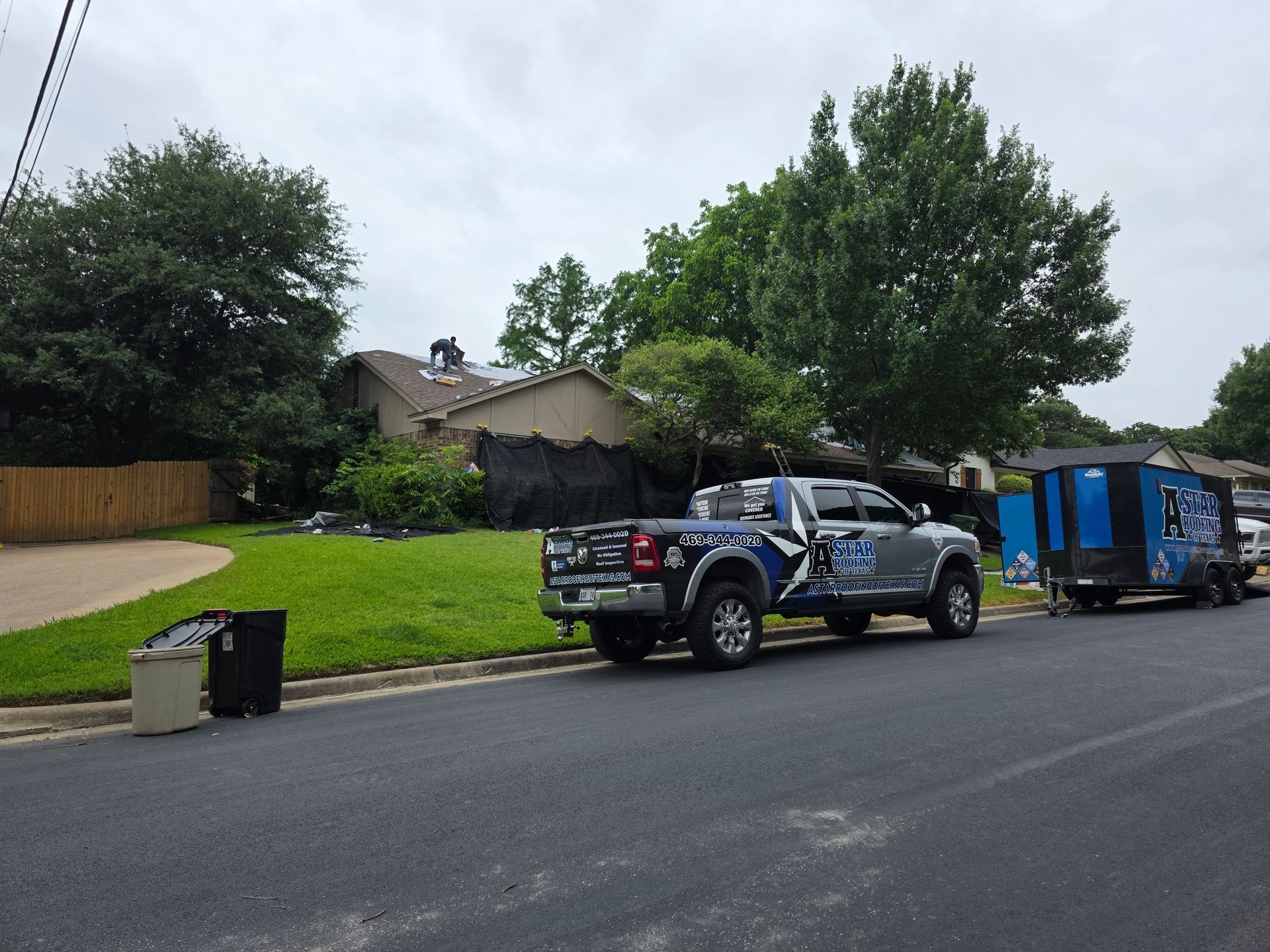Two trucks are parked on the side of the road in front of a house.