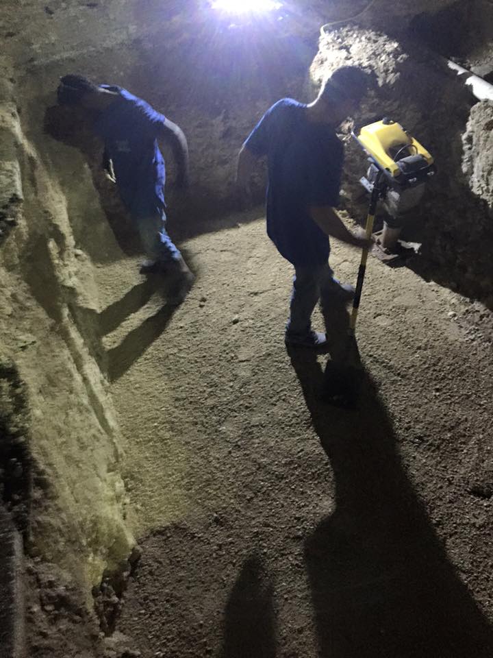 Two men are working in a cave at night.
