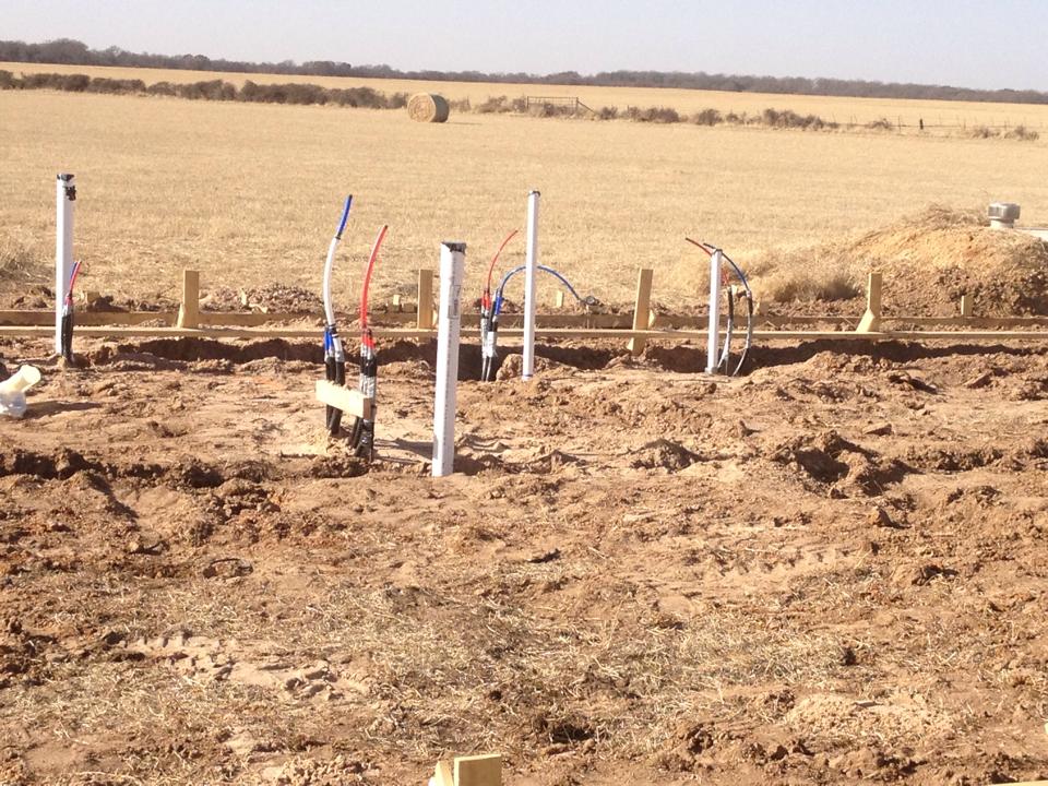 A row of pipes in the dirt with a field in the background