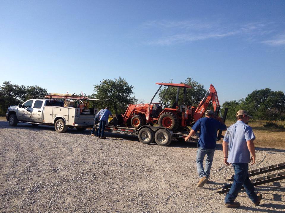 A tractor on a trailer is being towed by a truck