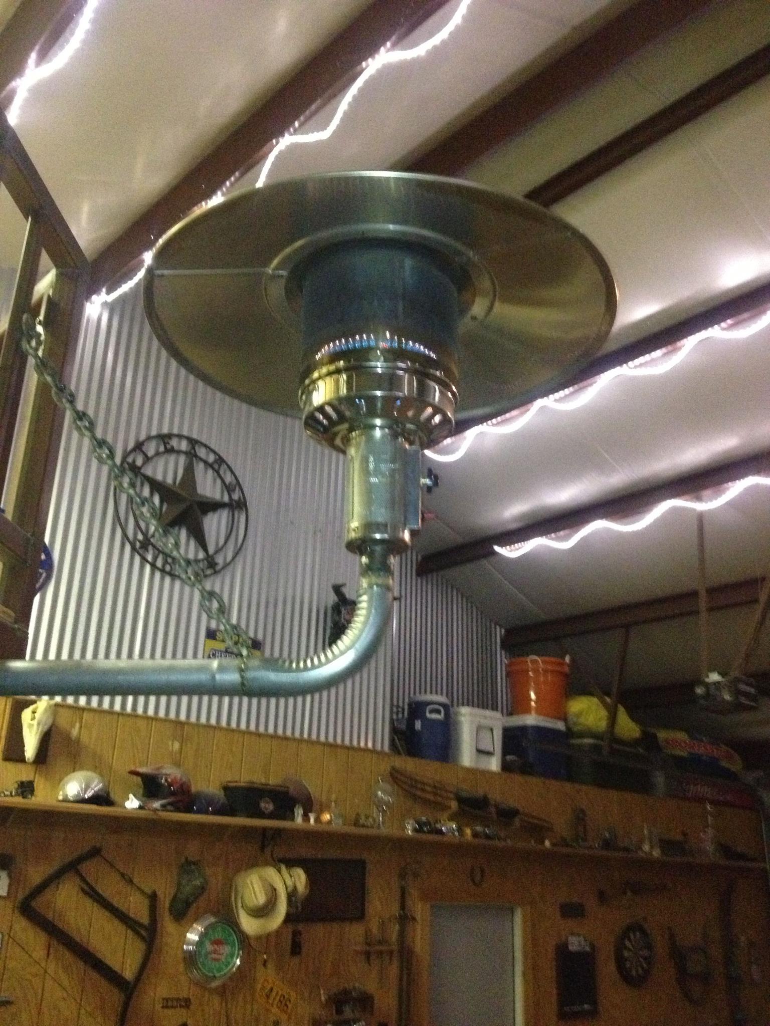 A heater is hanging from the ceiling in a garage
