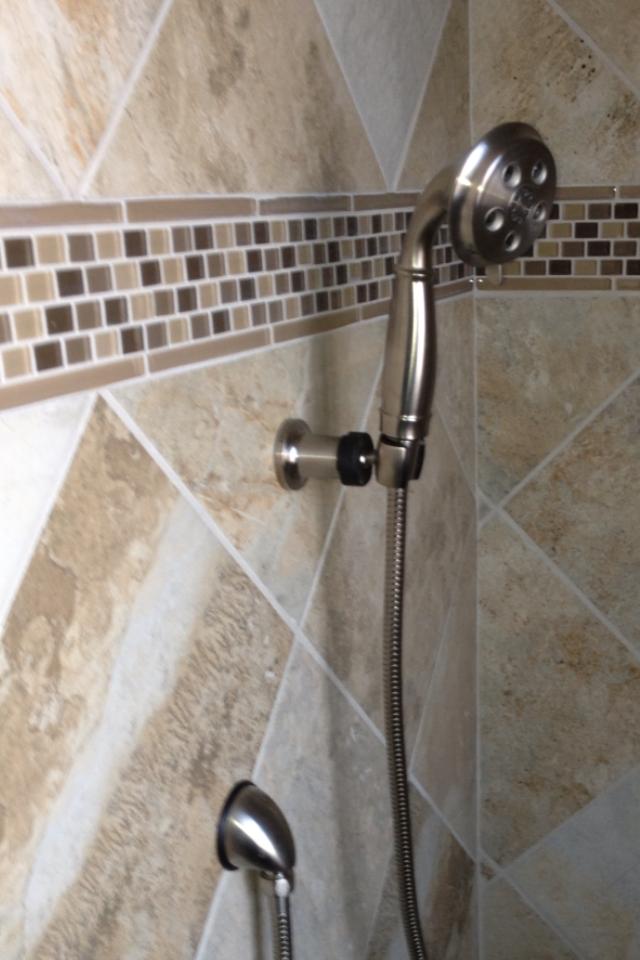 A shower head is attached to a tiled wall