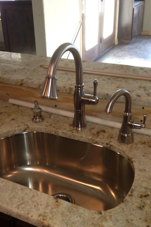 A stainless steel sink with two faucets on a granite counter top.