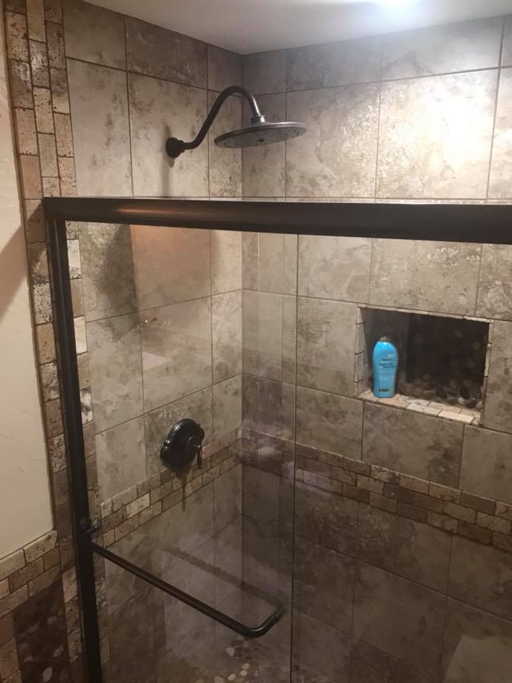 A shower with a sliding glass door and a shower head.