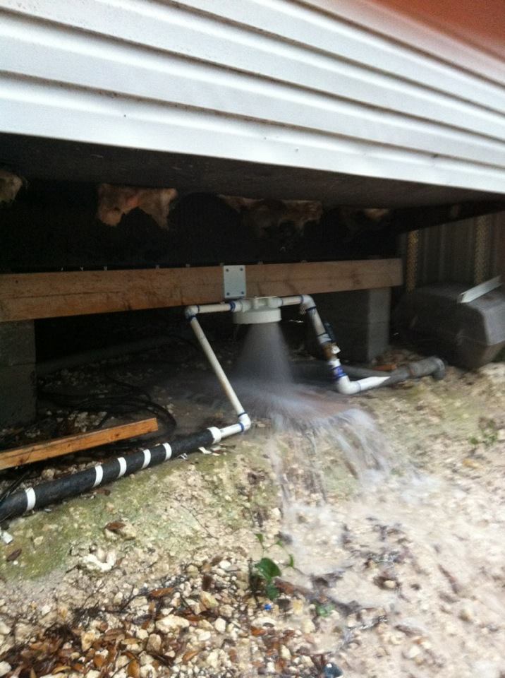 Water is coming out of a pipe under a house.