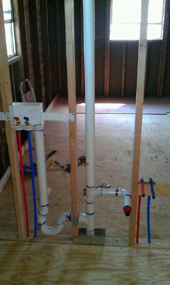 A bathroom under construction with a lot of pipes and faucets.