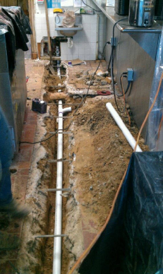 A pipe is being installed in the dirt in a kitchen.