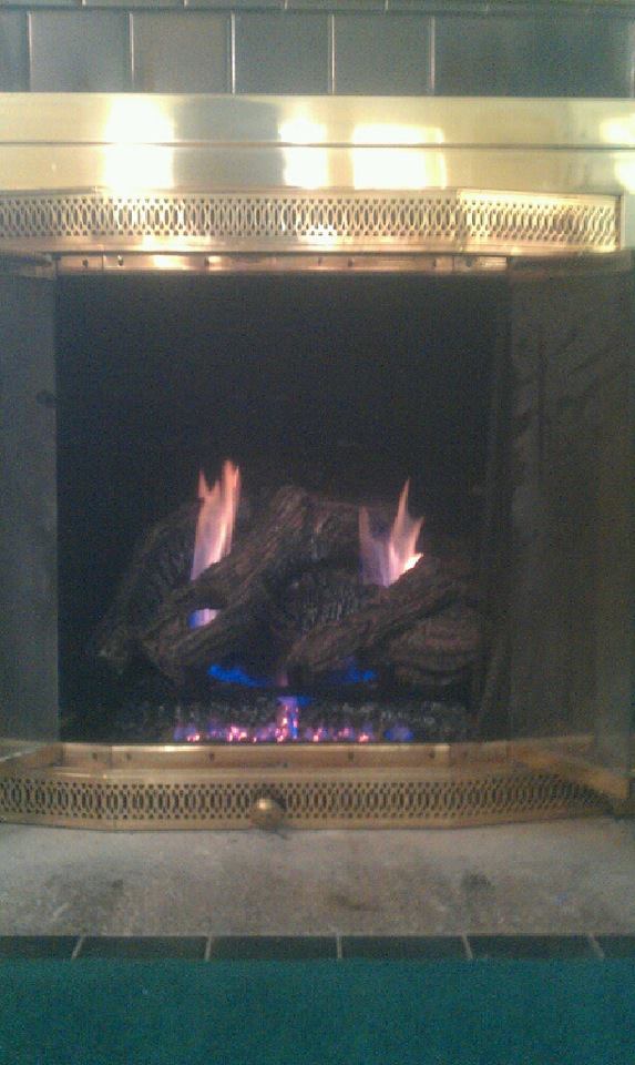 A fireplace with logs in it and flames coming out of it