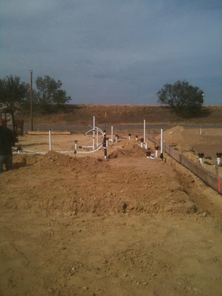 A construction site with a lot of pipes in the dirt