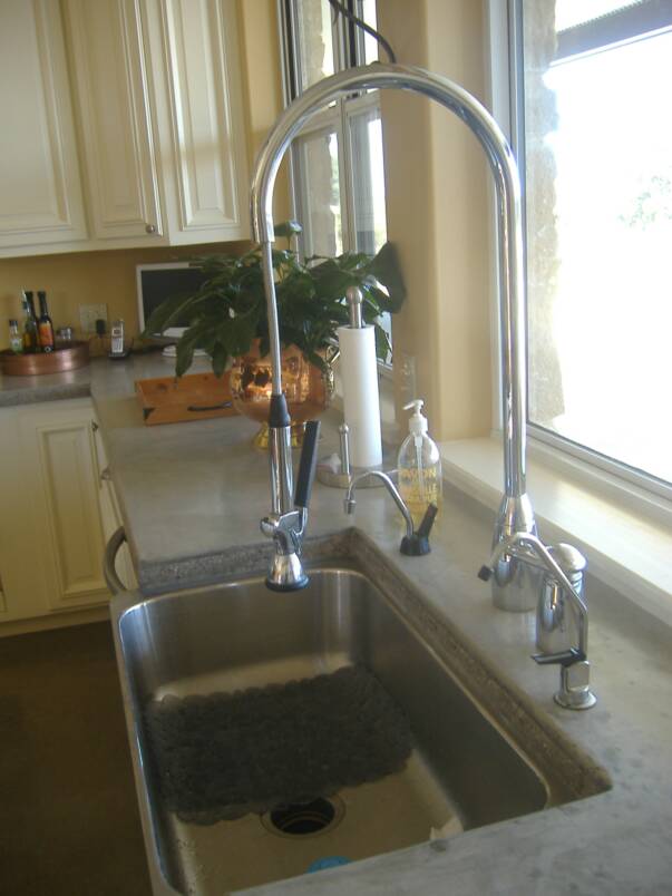 A kitchen sink with a faucet and soap dispenser