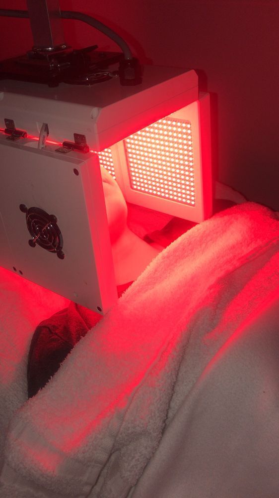A person is laying in bed with a red light on their face.