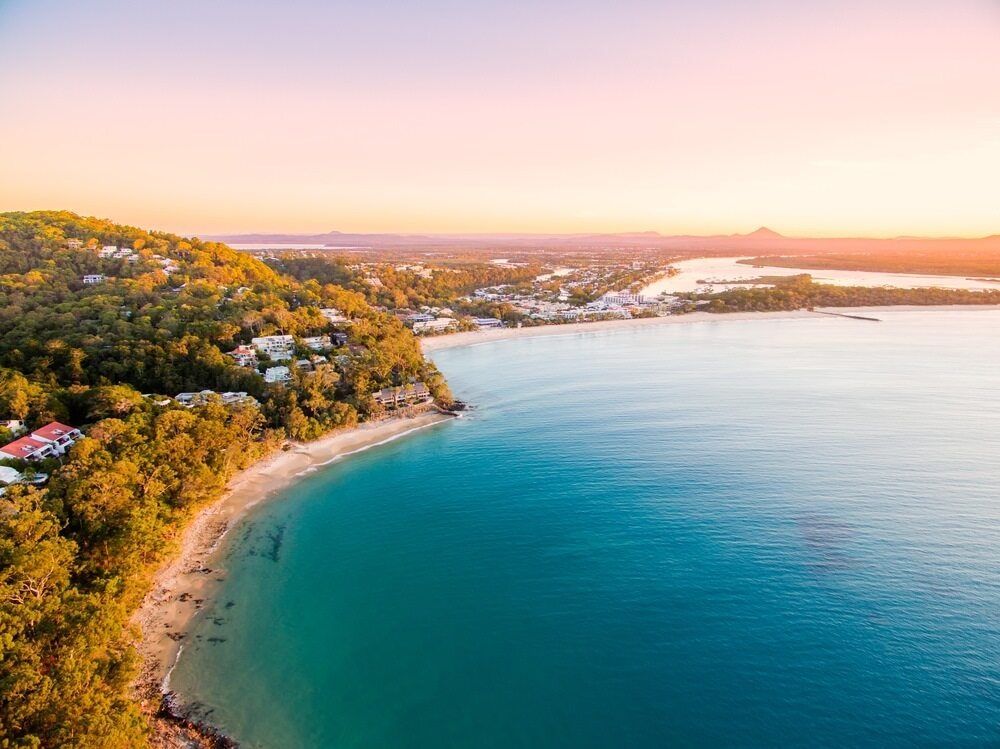 An Aerial View Of A Beach And A Body Of Water At Sunset — Homemakers Lifestyle In Noosa, QLD