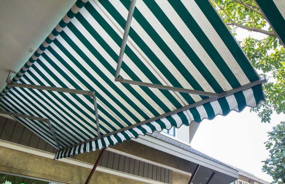 A Green And White Striped Awning Is Hanging From The Roof Of A Building — Homemakers Lifestyle In Maroochydore, QLD
