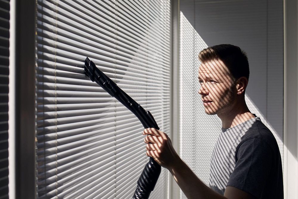 Man Cleaning dust from Window blind by Vacuum cleaner — Homemakers Lifestyle Maroochydore In Maroochydore QLD
