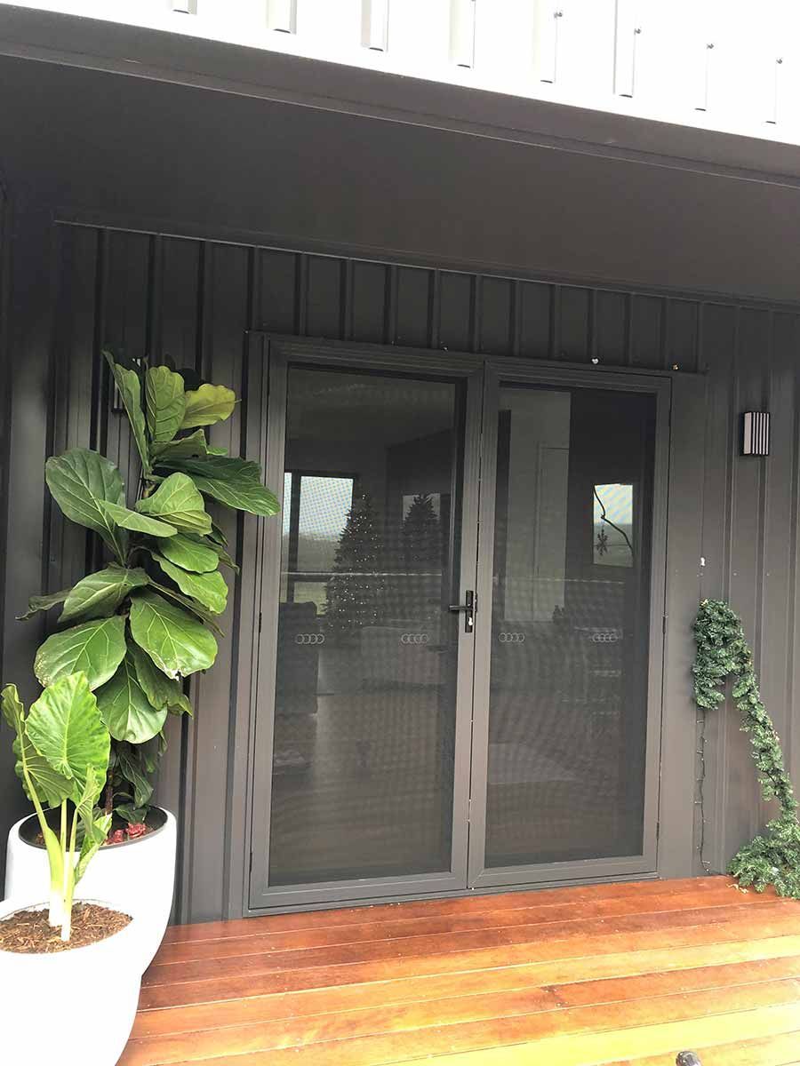A Potted Plant Is Sitting On A Wooden Porch Next To A Sliding Glass Door — Homemakers Lifestyle In Maroochydore, QLD