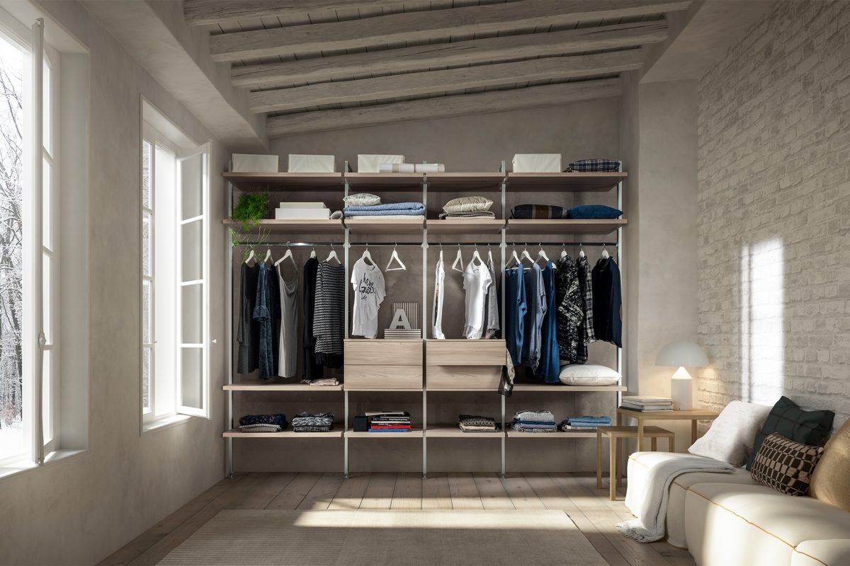 Un soggiorno con un divano e un armadio pieno di vestiti.