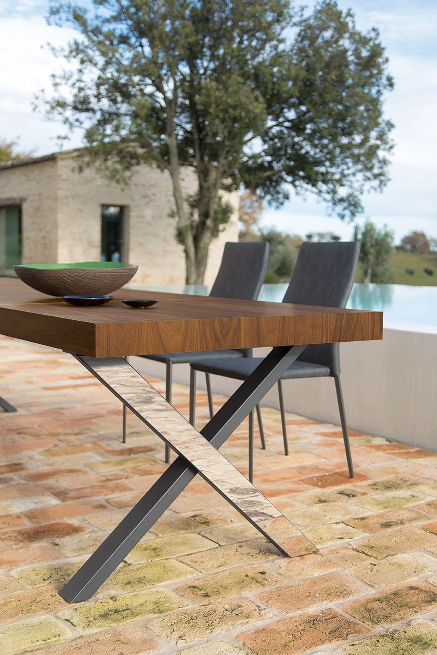 Un tavolo e delle sedie di legno sono posizionati su un patio in mattoni.