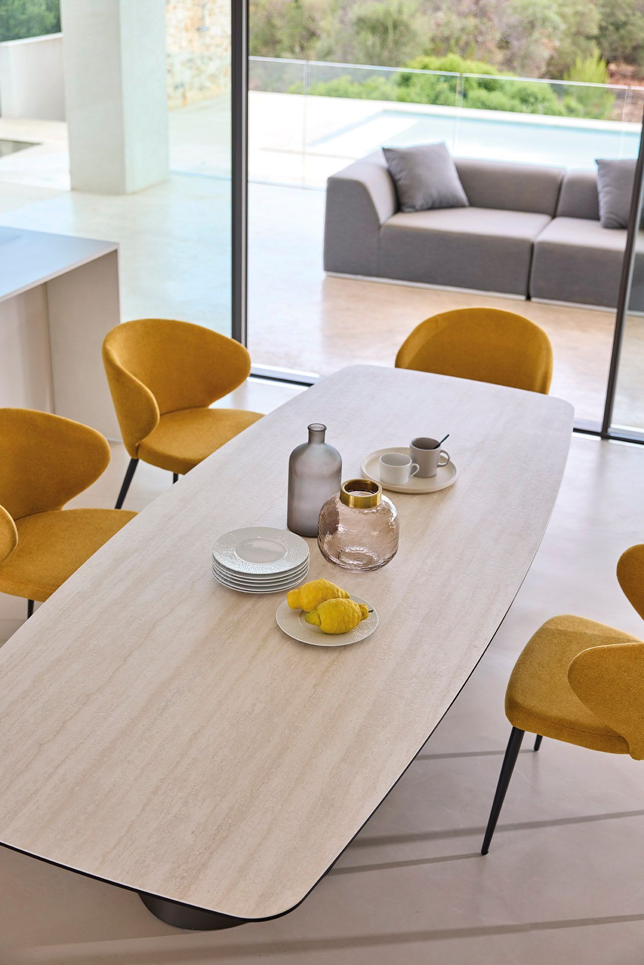 Un tavolo da pranzo con sedie gialle e un divano sullo sfondo.