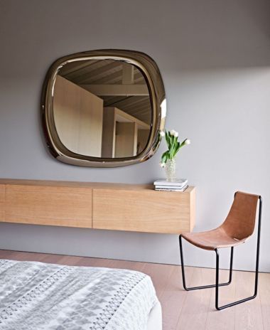 Una camera da letto con un grande specchio e una sedia