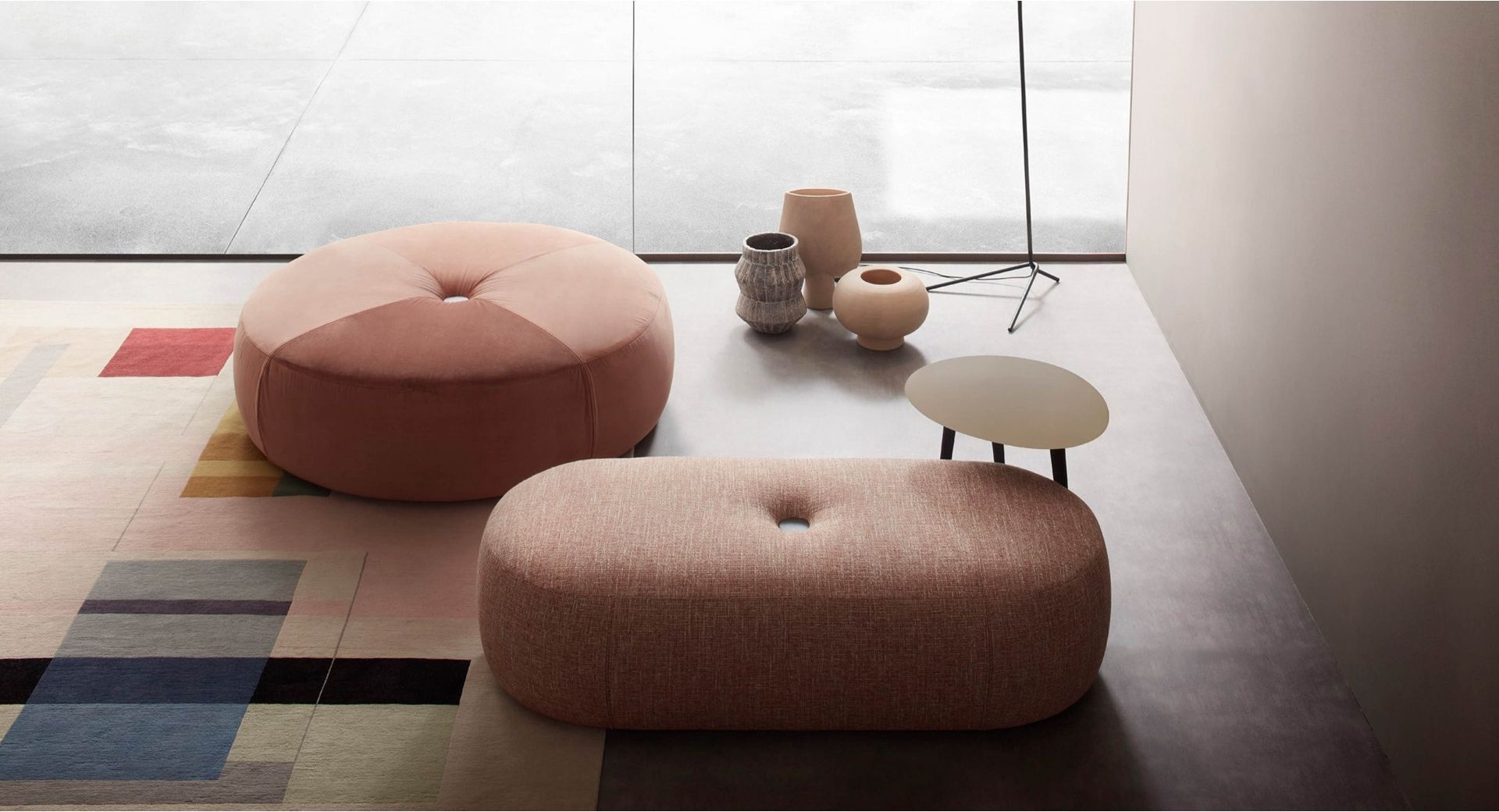 Due pouf rosa sono appoggiati su un tappeto accanto a un tavolino.