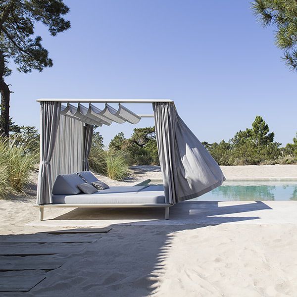 Un letto a baldacchino si trova sulla spiaggia accanto a una piscina