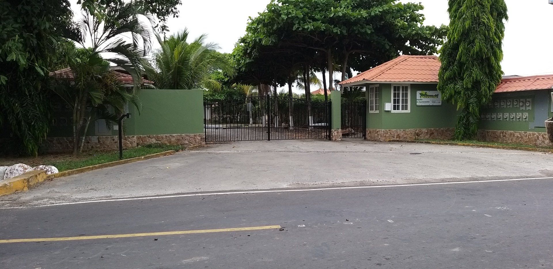 Un estacionamiento vacío con un edificio verde al fondo.