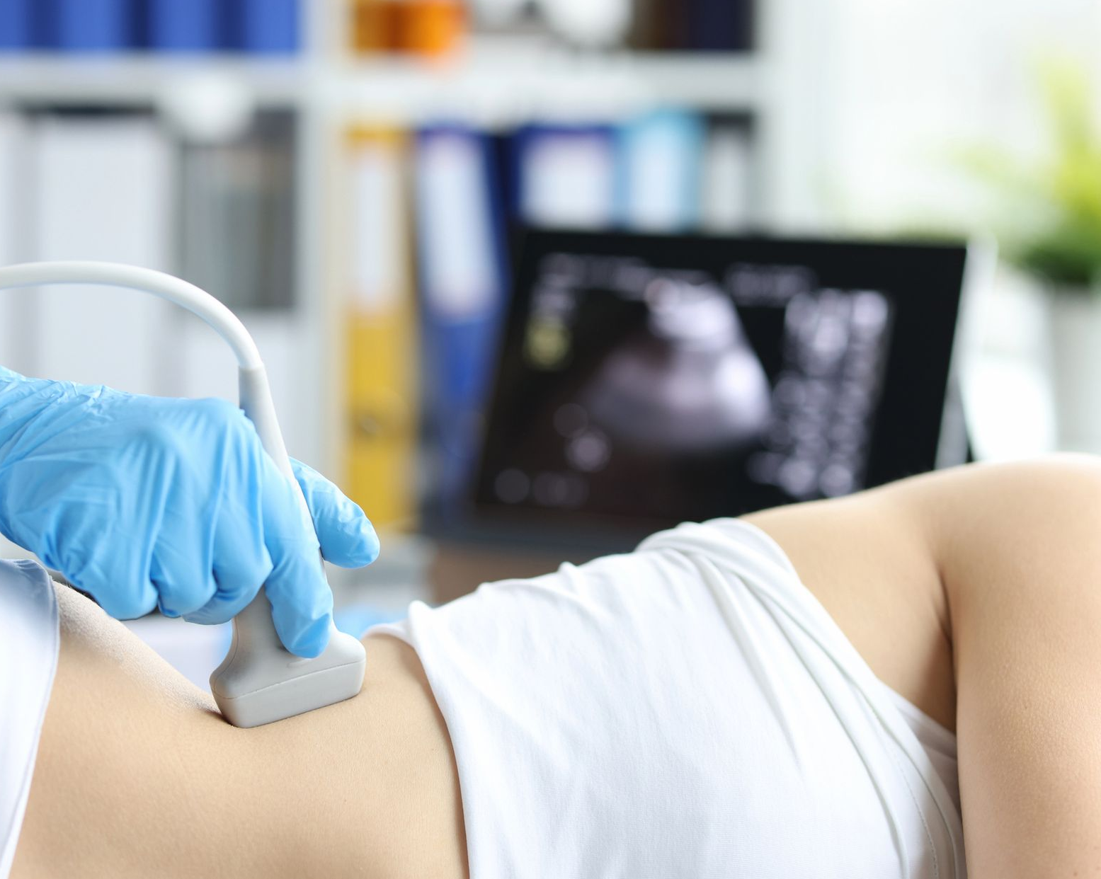 Il medico esegue un'ecografia sull'addome del paziente, sullo schermo vengono visualizzati i risultati della scansione.