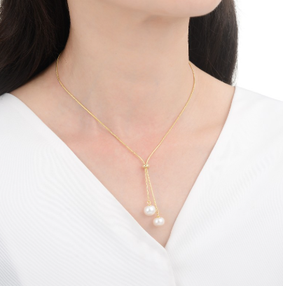 Collar de lazo dorado con dos perlas blancas colgando en la parte inferior.