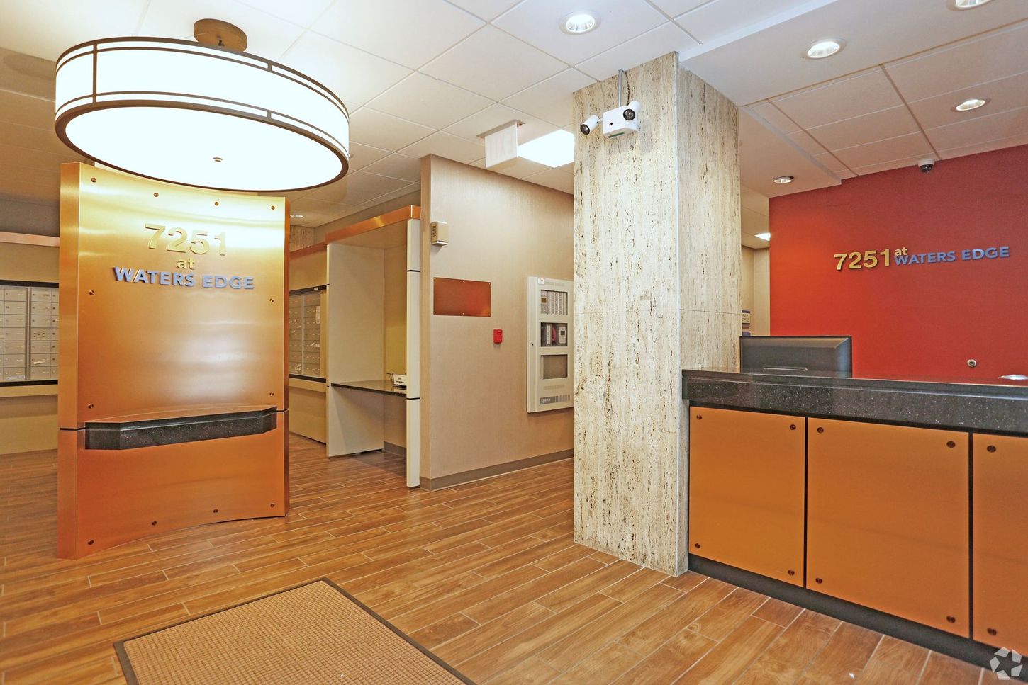 Office lobby with a wooden floor, reception desk, and signage for