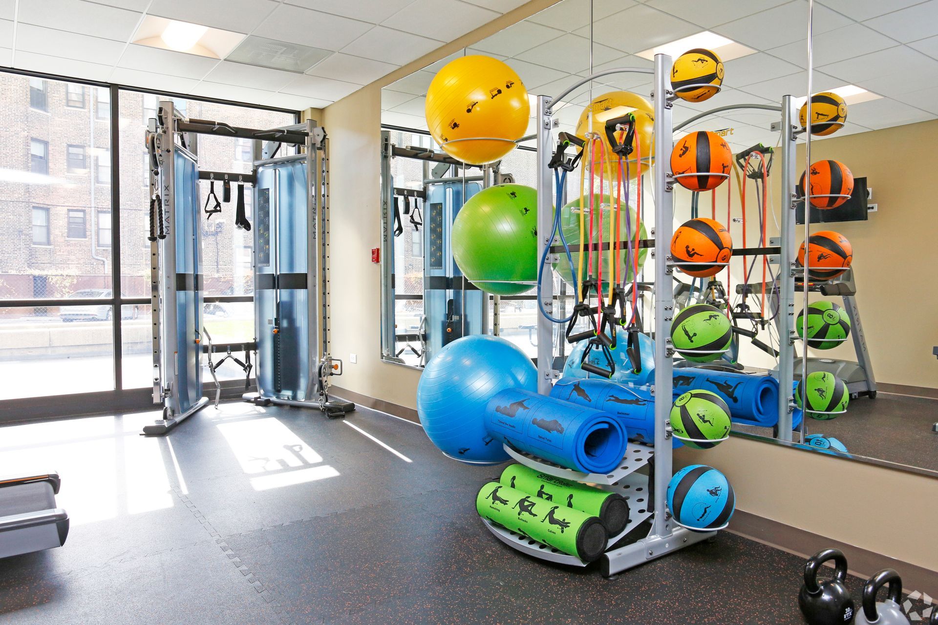 Gym with exercise equipment, including balls, weights, and a cable machine.
